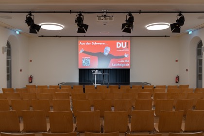 Leerer Saal mit Bestuhlung und Leinwand vor Beginn