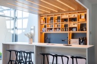 Kaffeebar mit beleuchtetem Holzregal und Barhockern