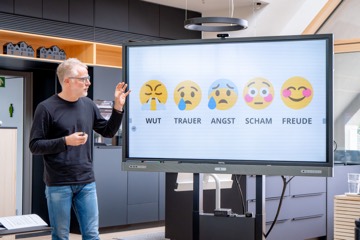 Trainer vor einer Folie mit fünf Emotionen von Wut bis Freude