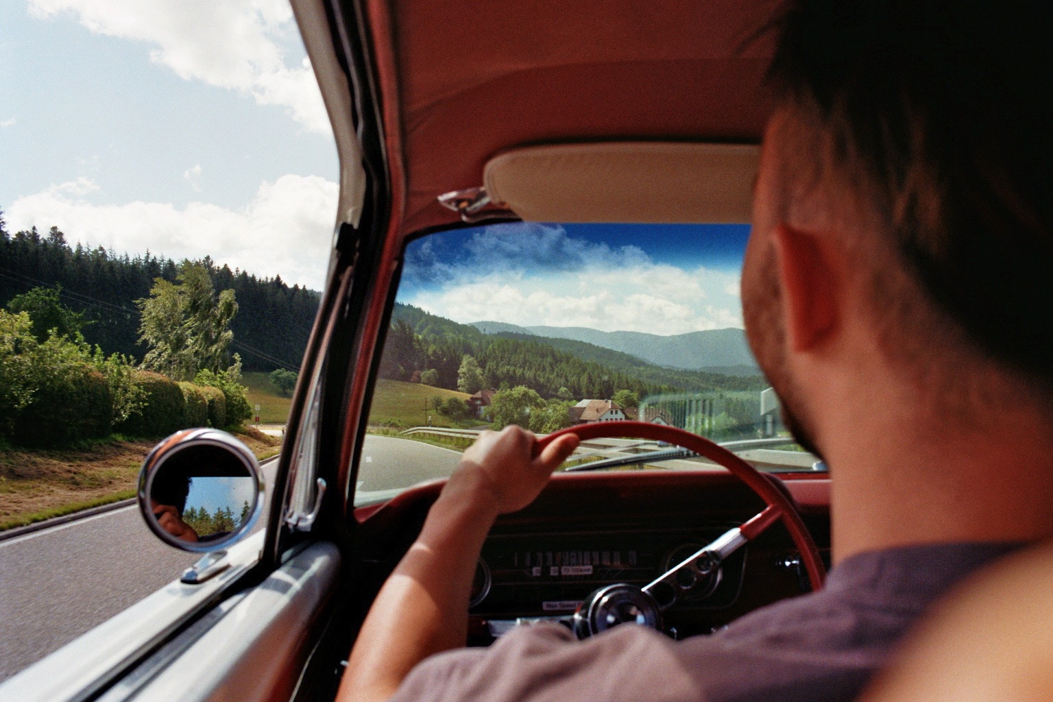Fahrer am Steuer eines Oldtimers auf der Landstraße