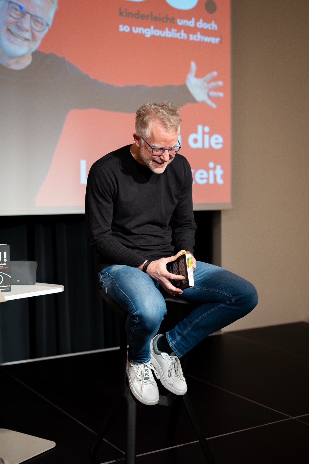 Redner liest auf dem Hocker aus seinem Buch