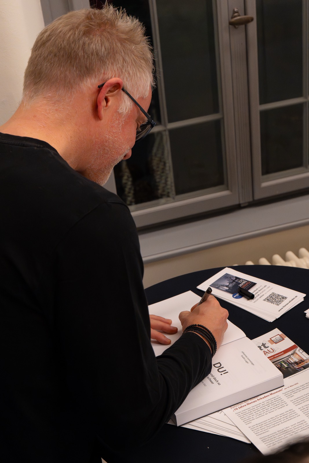 Autor signiert ein Buch am Tisch