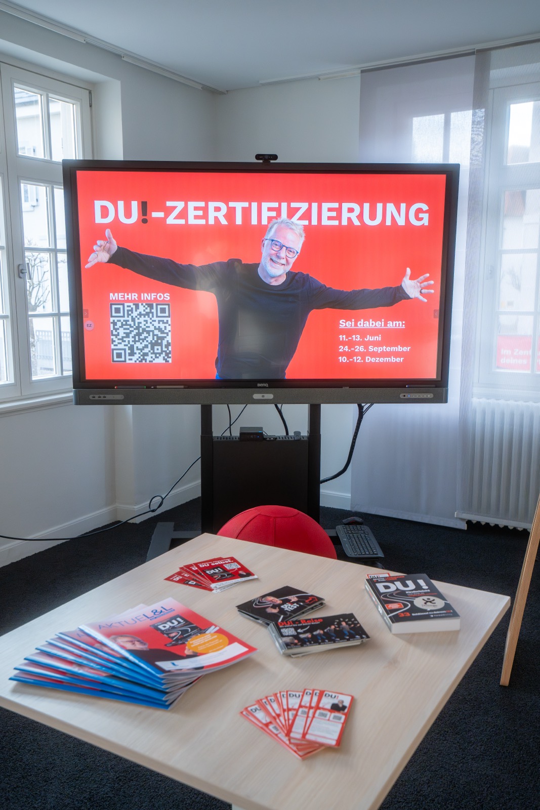 Bildschirm zur DU!-Zertifizierung, davor Bücher auf dem Tisch