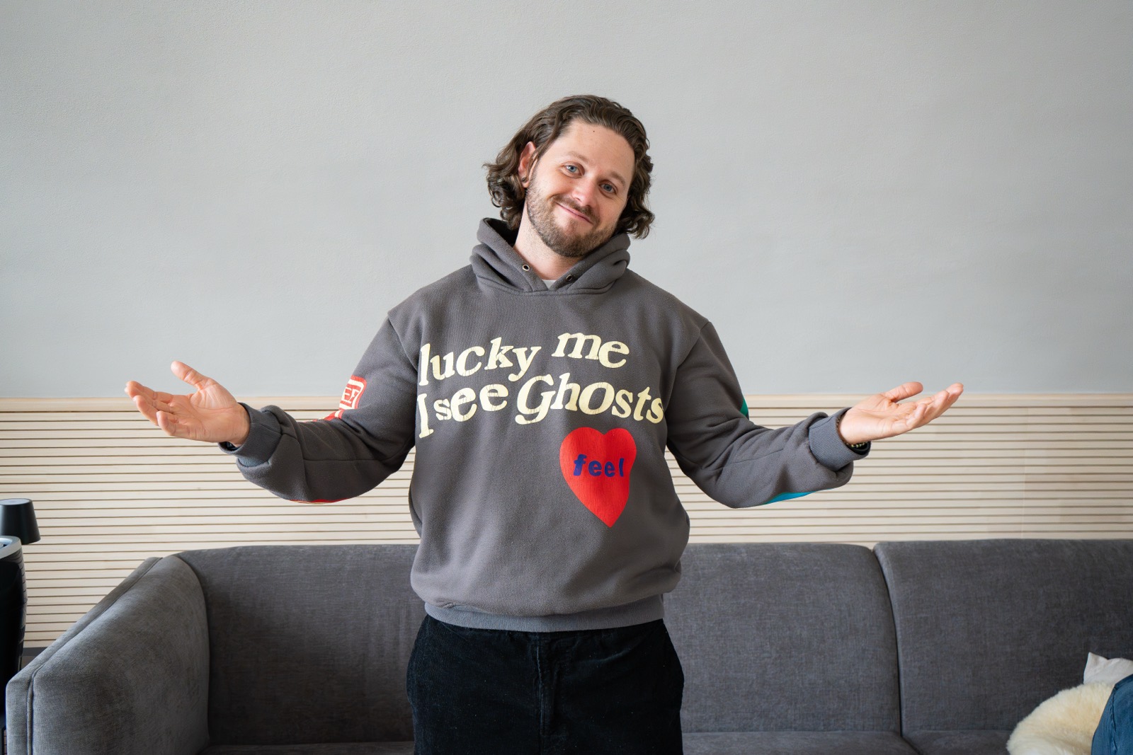Teilnehmer im Hoodie breitet lachend die Arme aus