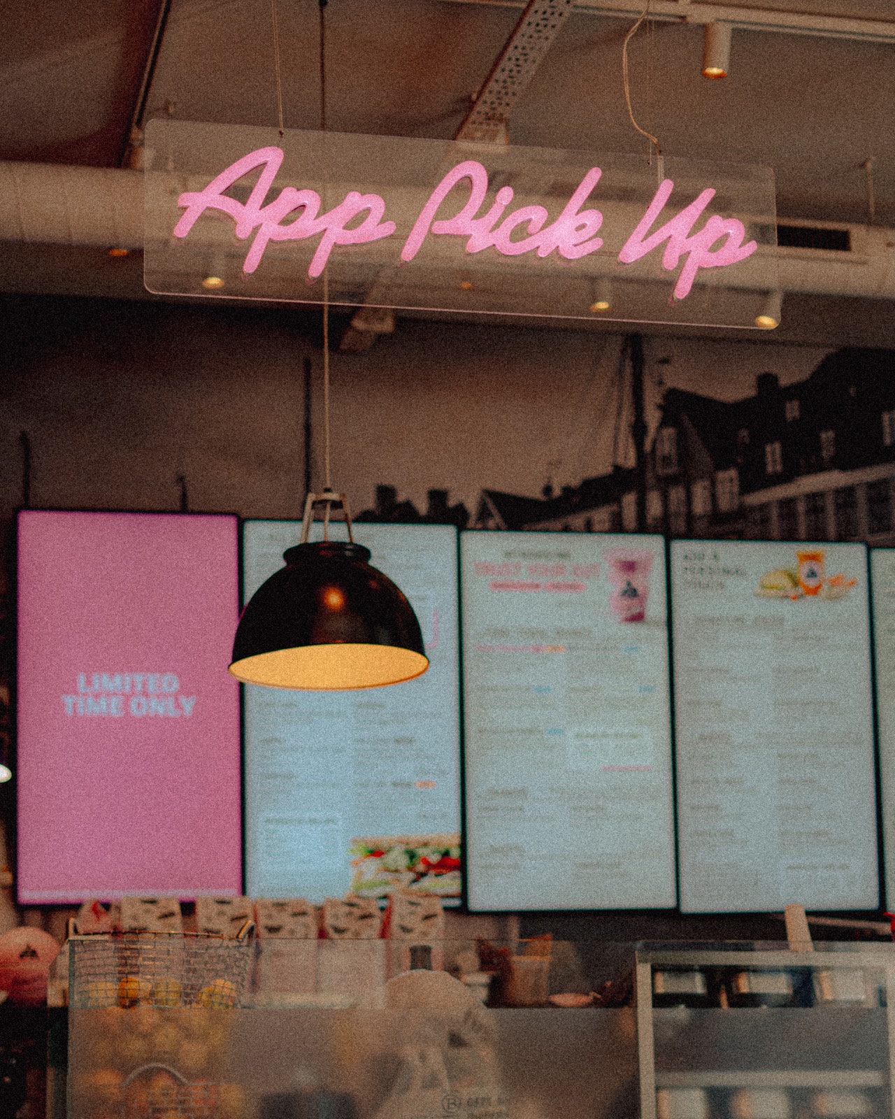 Neonschrift „App Pick Up“ über einer Theke