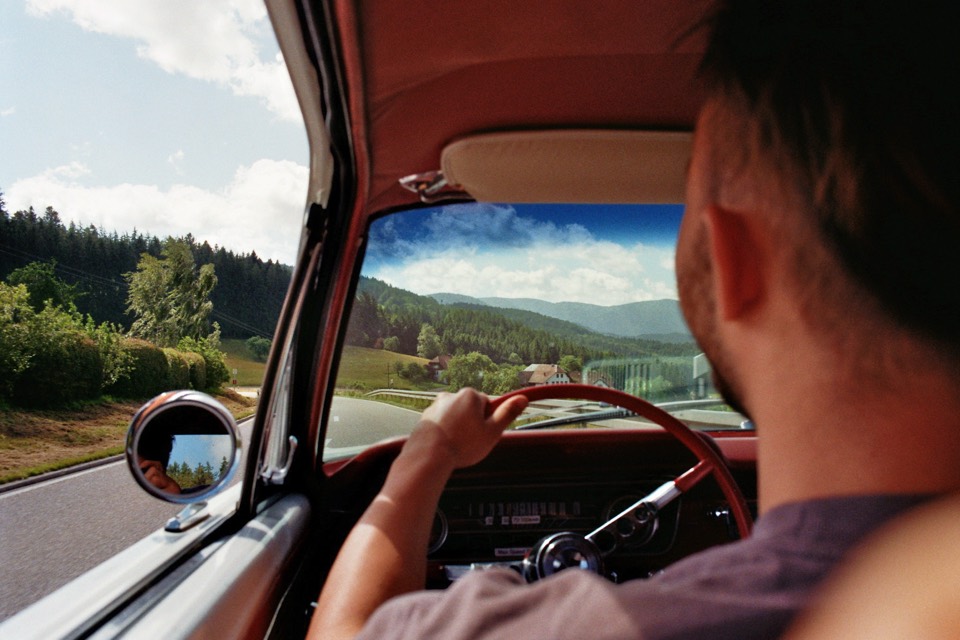 Fahrer am Steuer eines Oldtimers auf der Landstraße