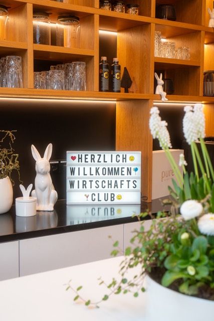 Schild „Herzlich willkommen Wirtschaftsclub“ an der Bar