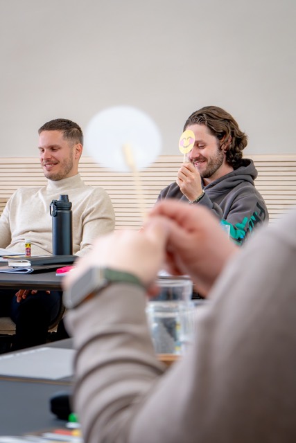 Teilnehmende lachen mit Emoji-Schildern in der Hand