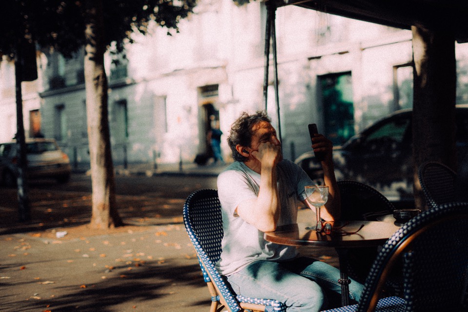 Frau lacht auf einer Caféterrasse im Gegenlicht