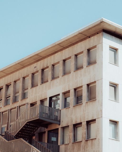 Fassade eines Nachkriegsbaus vor blauem Himmel